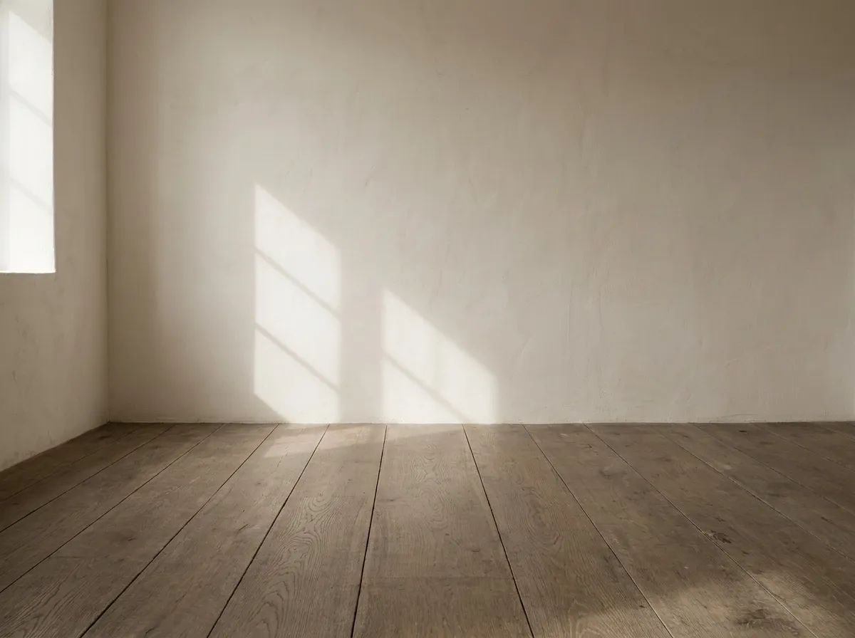 Pale wall meeting a wide oak floorboard in diffused daylight